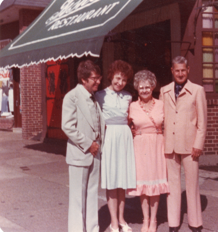 Two men and two women smile together outside of a restaurant