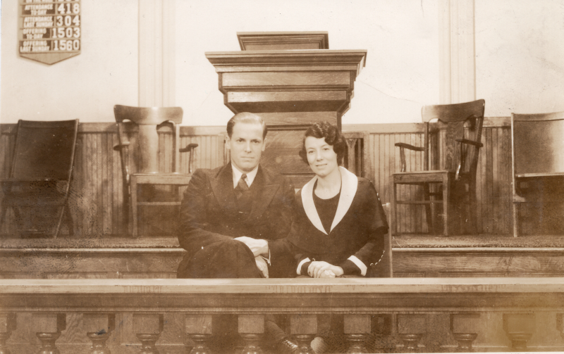 A man and woman pose together in front of the pulpit and behind the altar