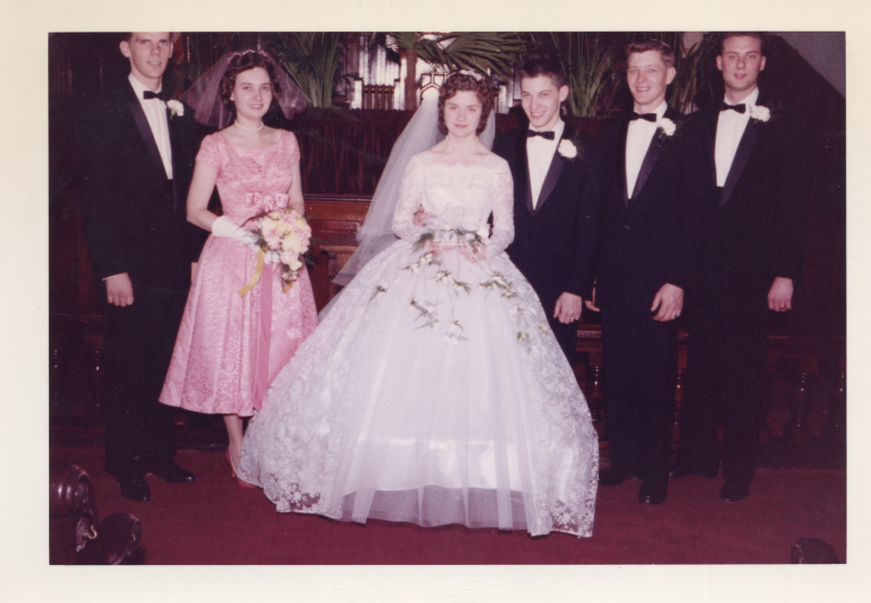 A bride and groom smile with members of their wedding party