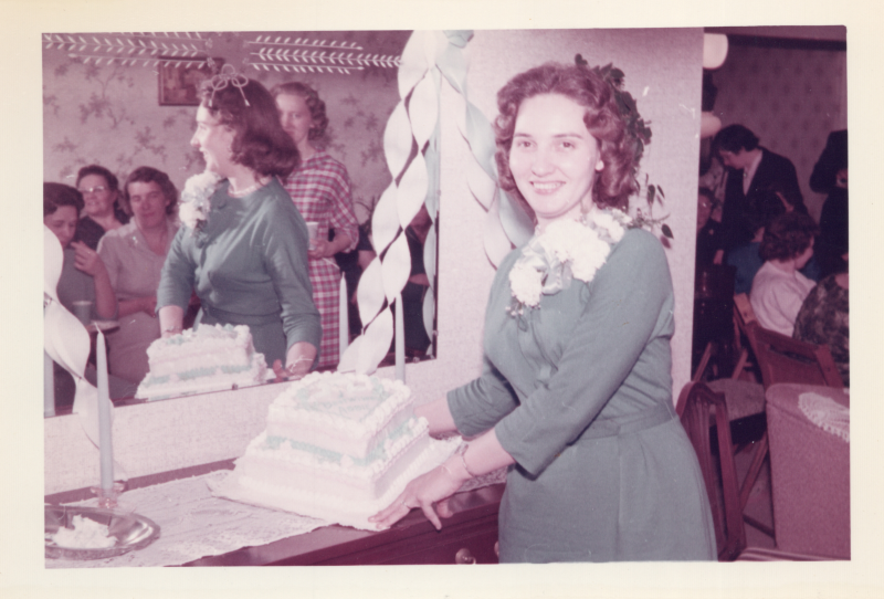 A woman carries a cake next to streamers