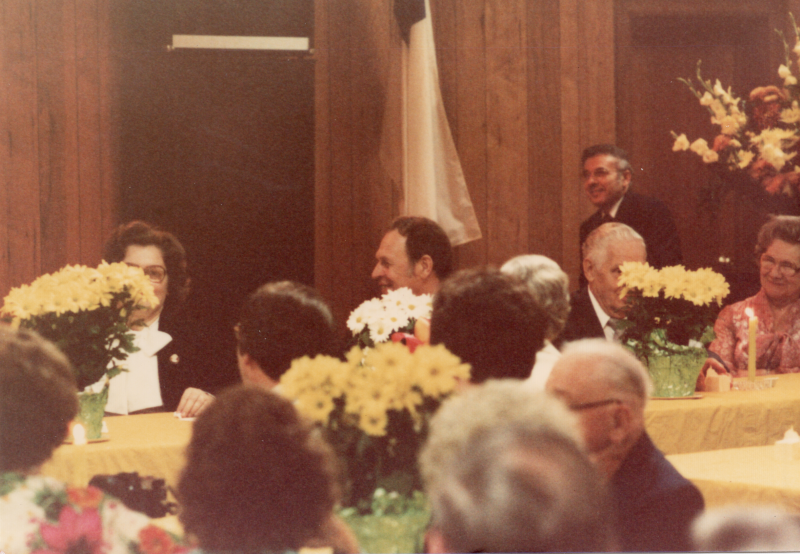 Congregants dine together at tables adorned with flowers