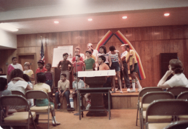 Children sing together on stage for a crowd of congregants