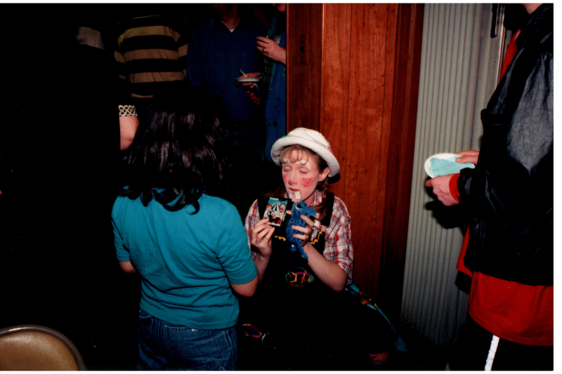 A woman dressed as a clown talks to a young girl