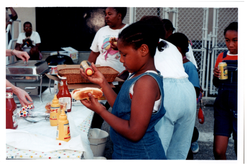 A girl puts mustard on a hot dog