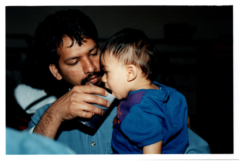A man gives a baby something to drink