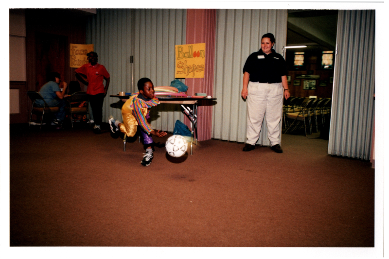 A girl in a clown outfit tosses a soccer ball
