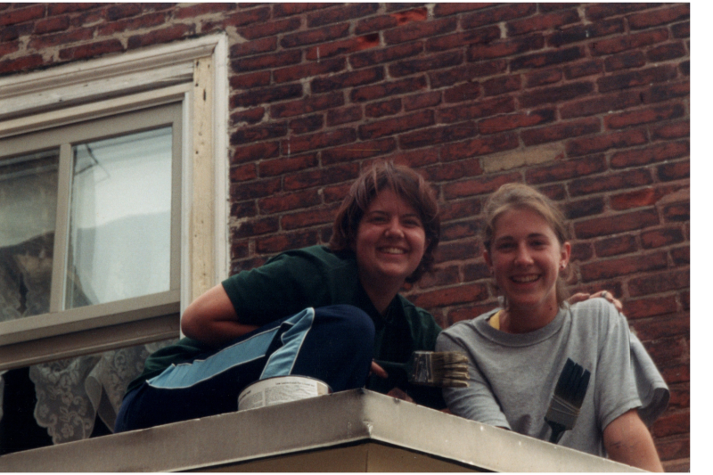 Women paint the parsonnage's exterior