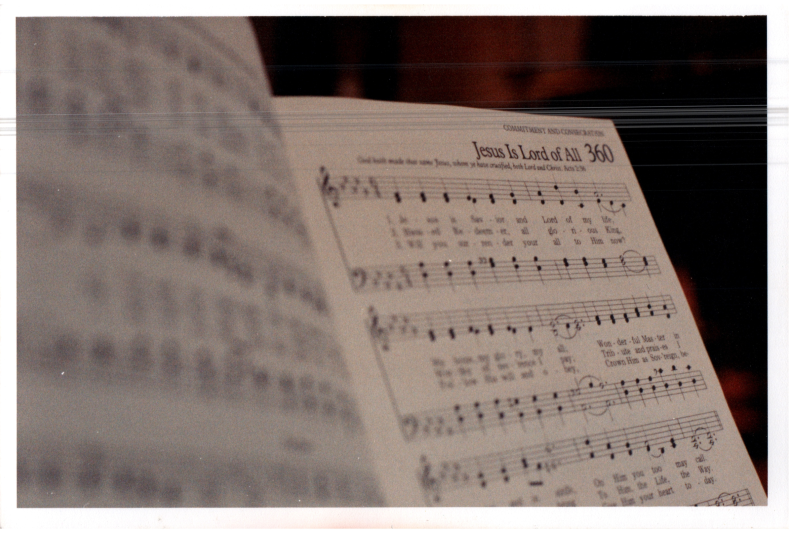 Photograph of a hymnal opened to Hymn 360, "Jesus is Lord of All"