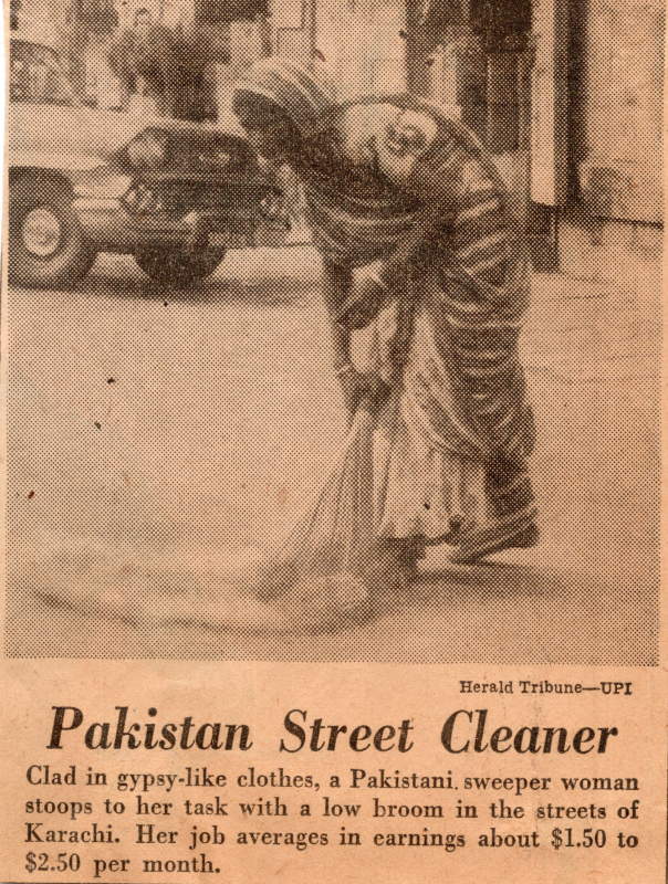 Image of a woman cleaning the street with the description, "Clad in gypsy-like clothes, a Pakistani sweeper woman stoops to her task with a low broom in the streets of Karachi. Her job averages earnings about $1.50 to $2.50 per month."
