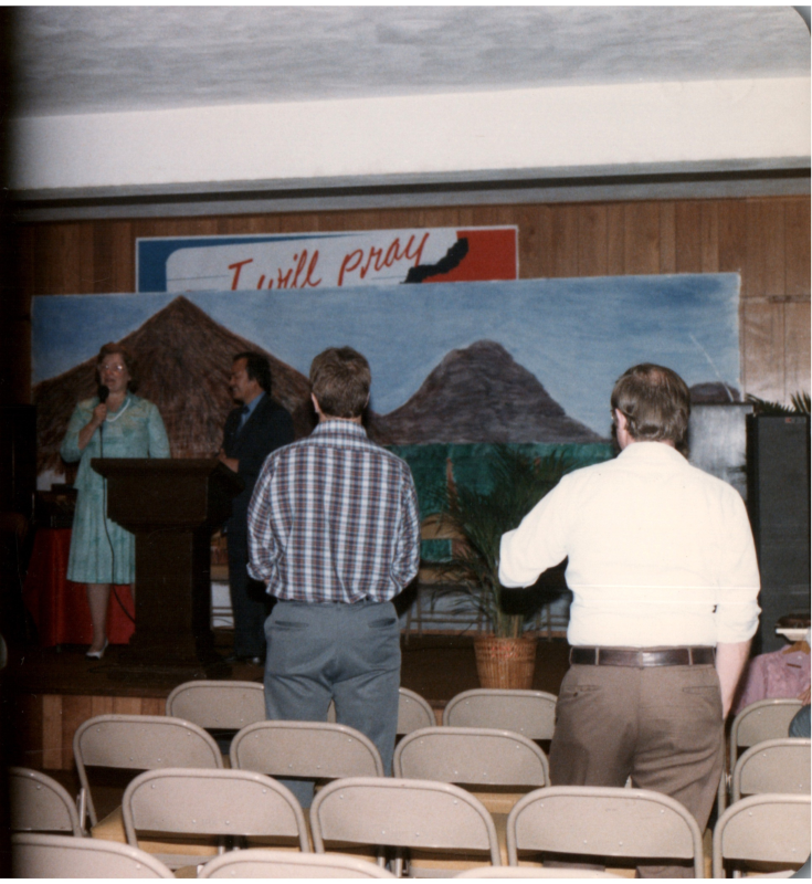 An audience faces Mrs. Bogdan and a man on stage