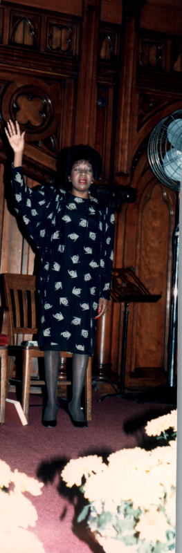 A woman in the sanctuary worships with her hand raised